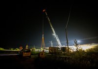 Nocny widok z ziemi na montaż metalowej konstrukcji wiaduktu kolejowo-drogowego nad drogą krajową nr 63 w Czyżewie.