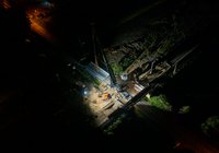 Nocny widok z powietrza na montaż metalowej konstrukcji wiaduktu kolejowo-drogowego nad drogą krajową nr 63 w Czyżewie.