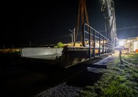 Nocny widok z ziemi na montaż metalowej konstrukcji wiaduktu kolejowo-drogowego nad drogą krajową nr 63 w Czyżewie.